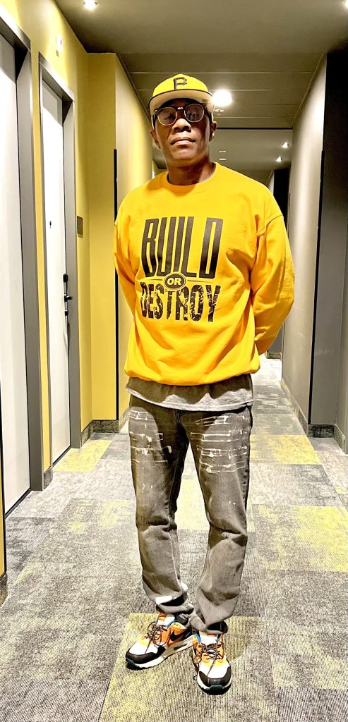 A man standing in an hallway wearing a yellow jacket.