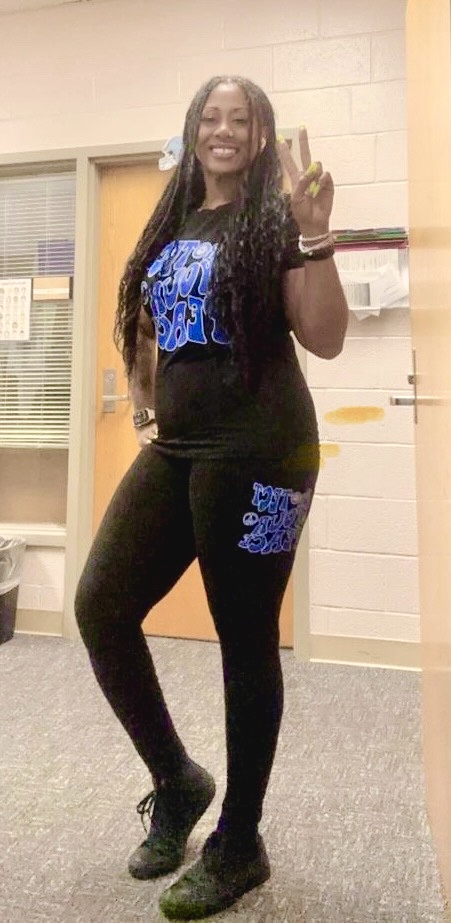 A woman in black and blue outfit standing next to a door.