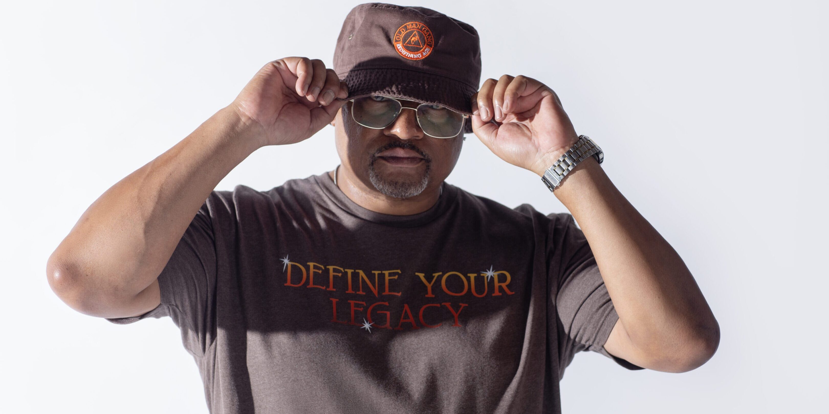 Man adjusting his cap wearing sunglasses and a graphic tee.